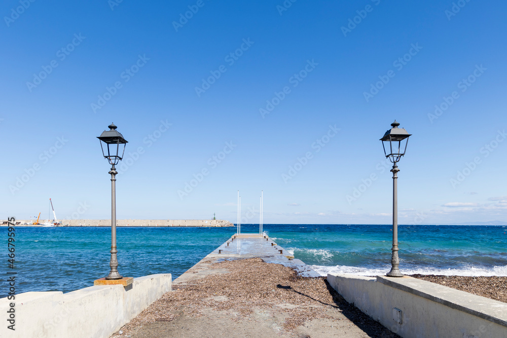 harbour pier washed over by waves with street lamps in Marciana Marina on the island of Elba