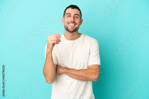 Young handsome caucasian man isolated on blue background laughing