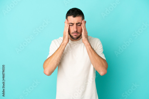 Young handsome caucasian man isolated on blue background with headache