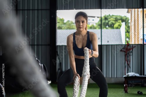 Female working out with battling rope at gym. Healthy modern people concept.