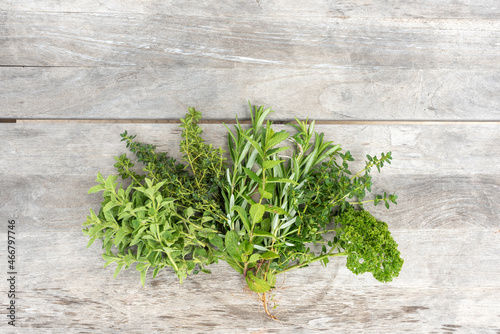 High angle view of freshly picked herbs on rough wooden table, including parsley, oregano, thyme and rosemary, with copy space