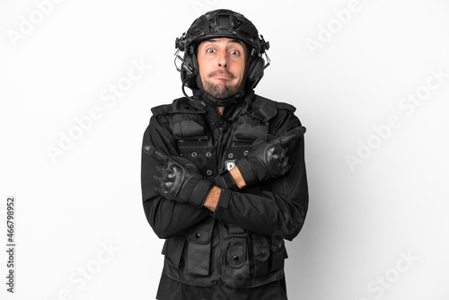 SWAT caucasian man isolated on white background pointing to the laterals having doubts © luismolinero