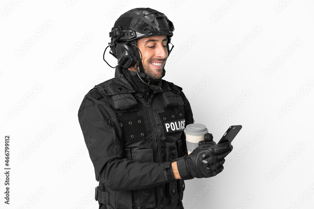 SWAT caucasian man isolated on white background holding coffee to take away and a mobile SWAT caucasian man isolated on white background holding coffee to take away and a mobile