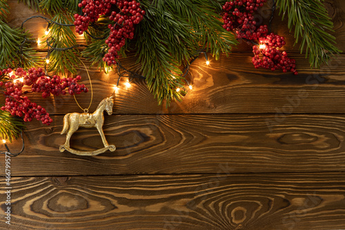 Wallpaper Mural Christmas background. Nobilis fir branches, twigs with red berries, toy golden horse on brown wooden planks. Copy space, flat lay, top view. Holiday, Xmas, New Year concept. Mockup Torontodigital.ca