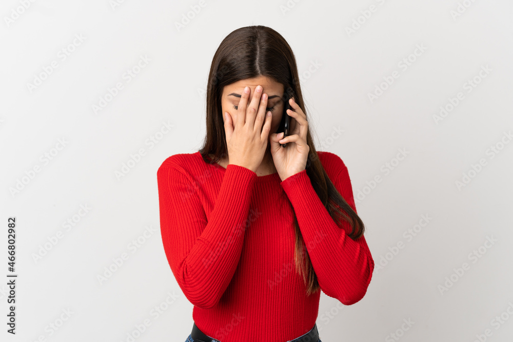 Teenager Brazilian girl using mobile phone over isolated white background with tired and sick expression Teenager Brazilian girl using mobile phone over isolated white background with tired and sick expression