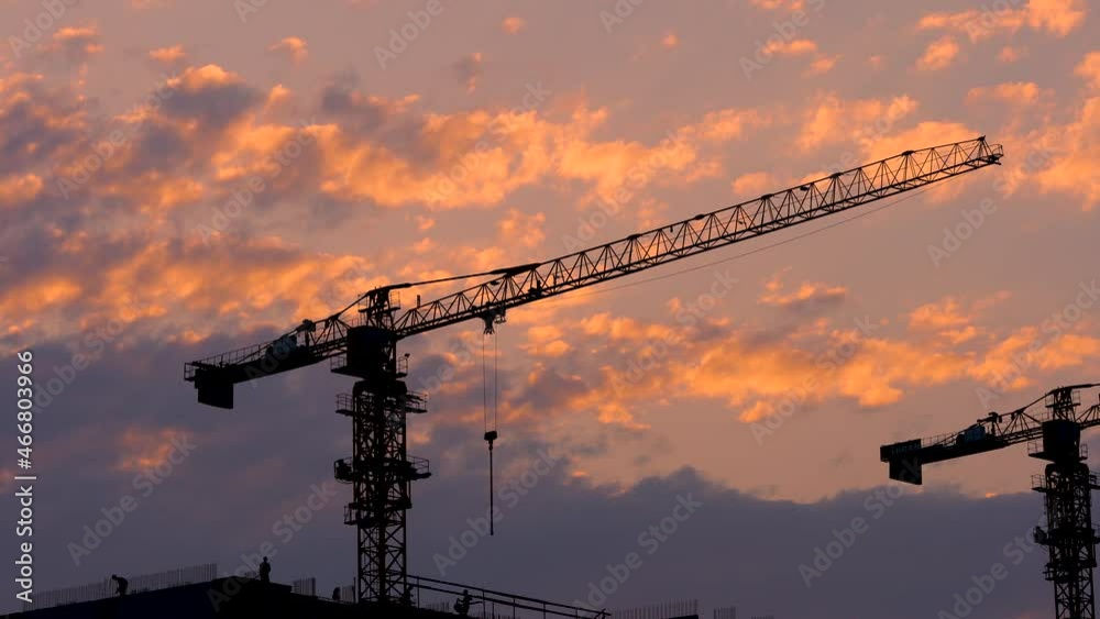 The construction site of an apartment building on the background of the sunset sky. Growth prospects. Silhouettes of a working crane. The construction site of an apartment building on the background of the sunset sky. Growth prospects. Silhouettes of a working crane.
