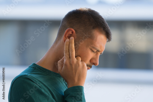 Man with tinnitus. Man touching his ear because of strong earache or ear pain. Otitis photo