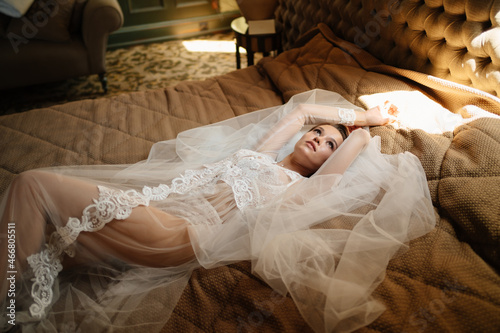 beautiful bride in a lace robe lies in bed on a veil. morning before the wedding