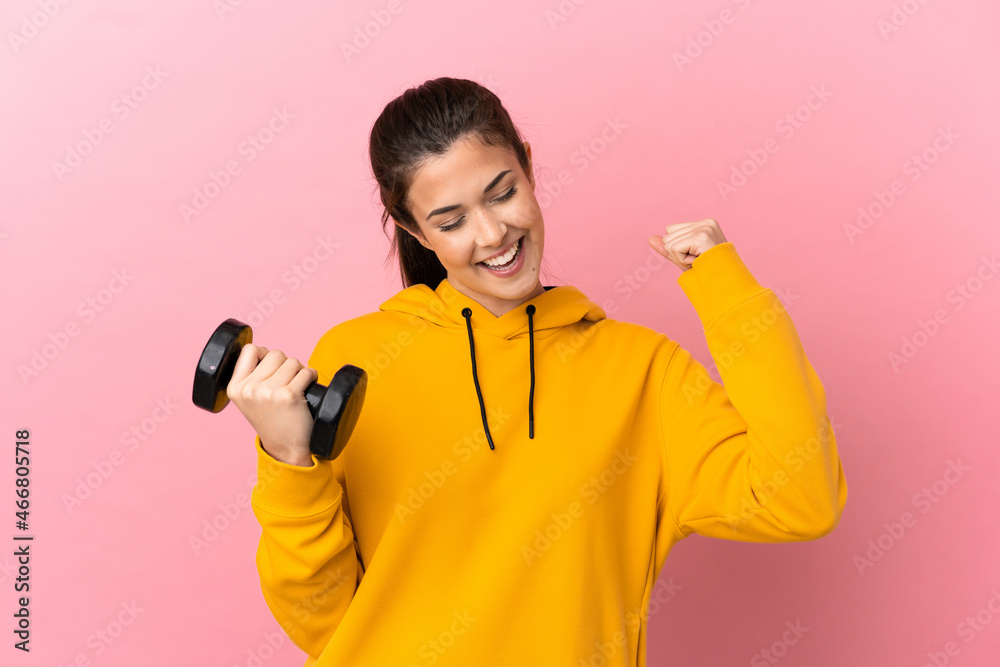 Young sport girl making weightlifting over isolated pink background celebrating a victory Young sport girl making weightlifting over isolated pink background celebrating a victory