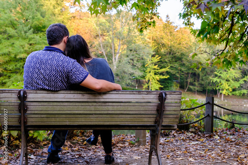 Couple sitting on bench and hugging each other in the forest, retirement concept idea with copy space