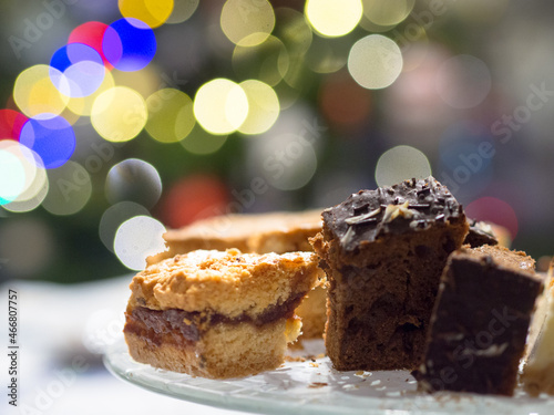 Pieces of cake on the plate. Bokeh christmas tree lights background
