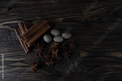 Natural cinnamon stick seasoning with anise stars and nutmeg on a brown wooden background, top view