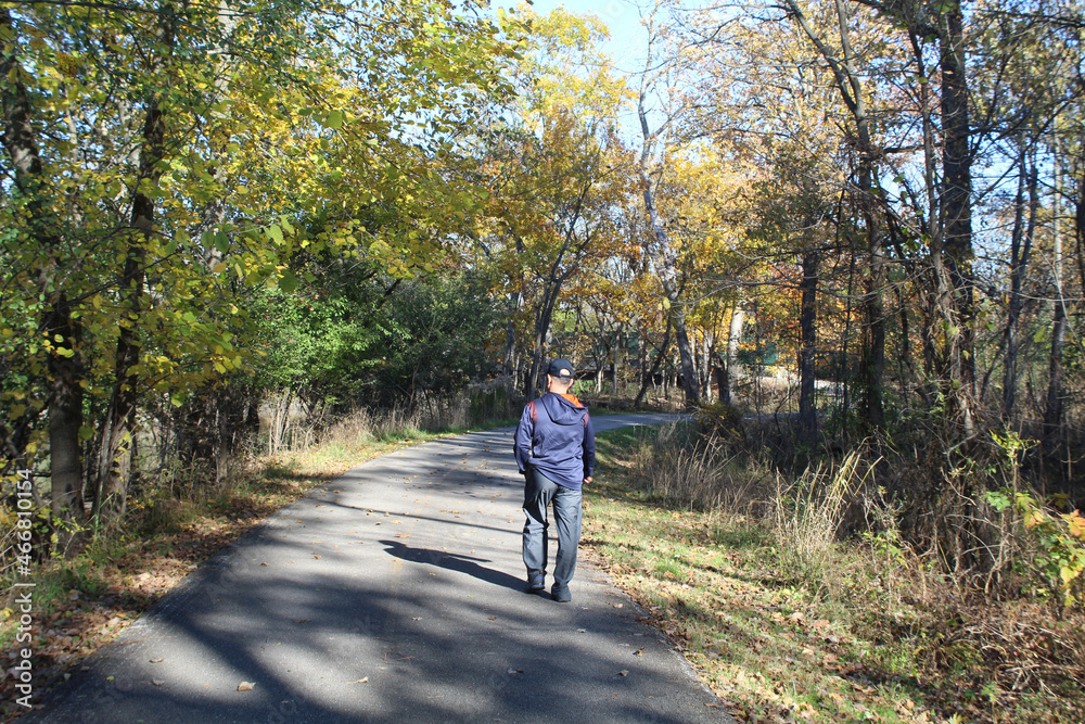 Middle-aged man walking on the North Branch trail in autumn at Blue Star Memorial Woods in Glenview, Illinois