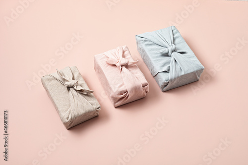 Zero waste gift wrapping traditional Japanese furoshiki style over pink background. Plastic free, hand made gift package for Christmas, birthday, Easter and other festive occasions
