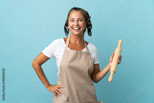 Middle age woman in chef uniform posing with arms at hip and smiling