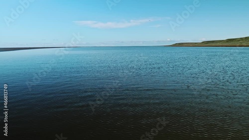 Landswell line of Kara sea in sunny afternoon on Yamal peninsula. Bright blue sky over the water photo