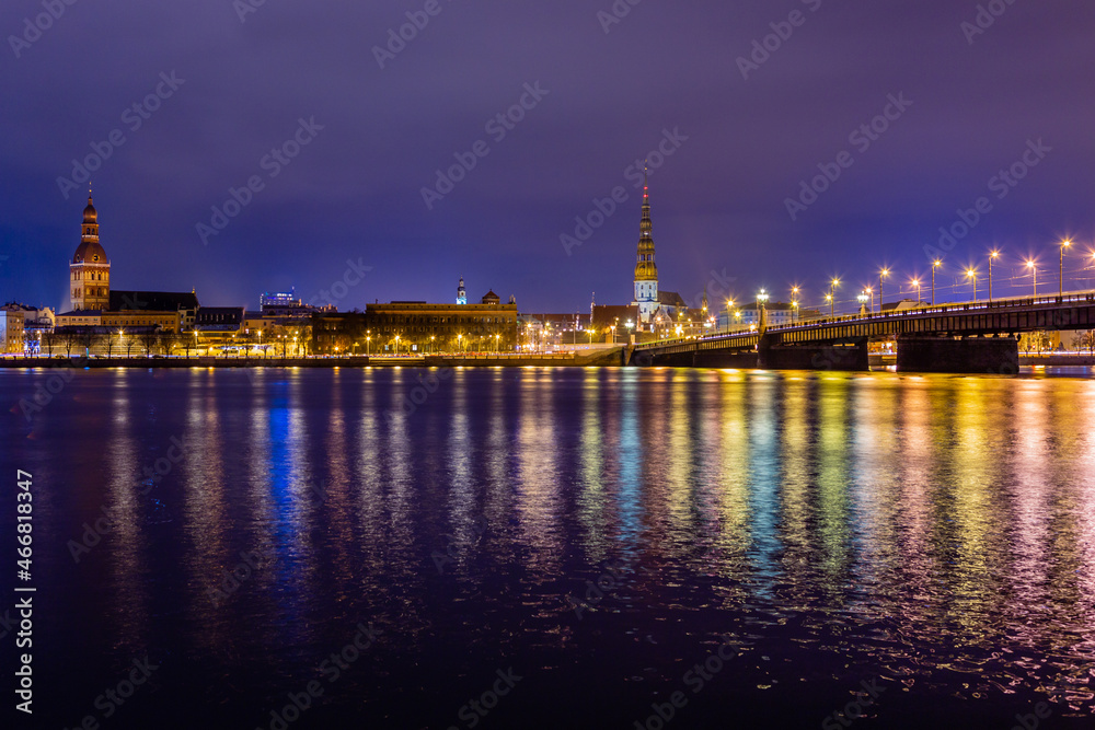 Night view to the historical city center and Stone bridge from the banks of Daugava river colored with street lights, Riga, Latvia