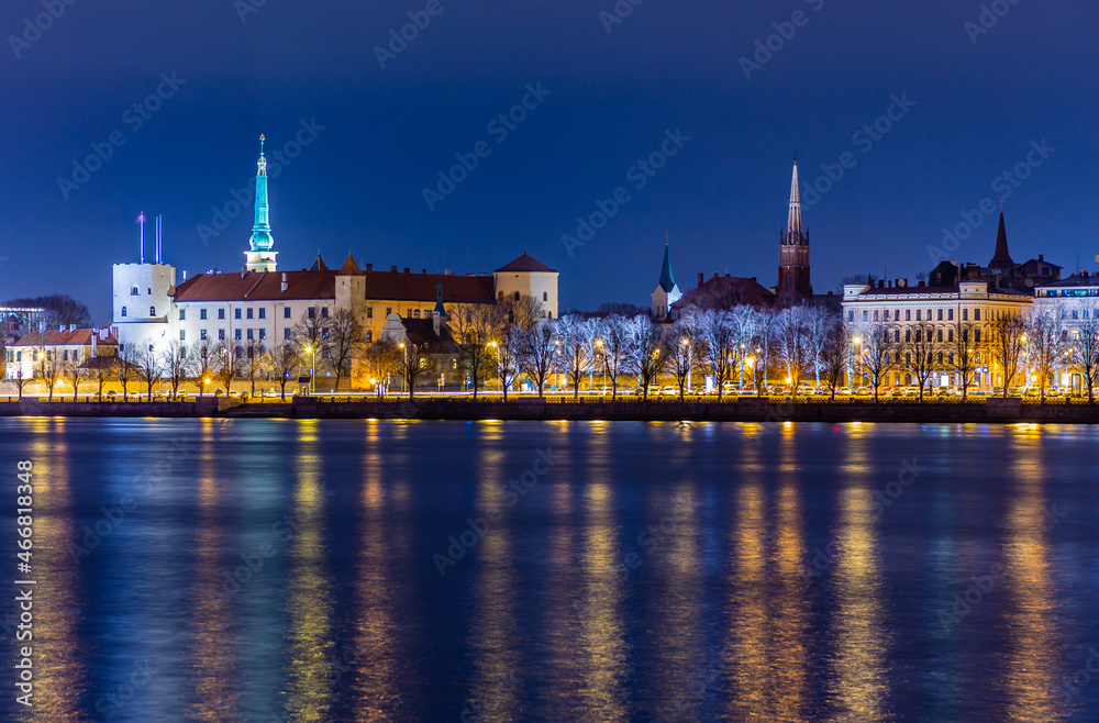 Night view to the historical city center with castle and churches  from the banks of Daugava river colored with street lights, Riga, Latvia