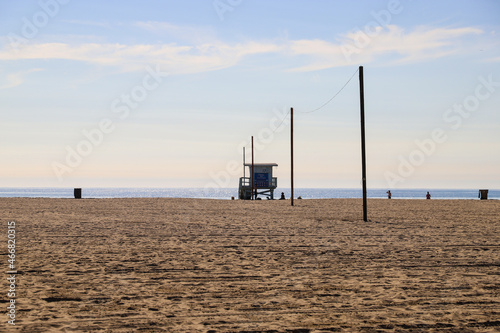 a gorgeous summer landscape at the beach with people relaxing in the sand and lifeguard towers with ocean water, blue sky and clouds at Santa Monica Beach in California USA
