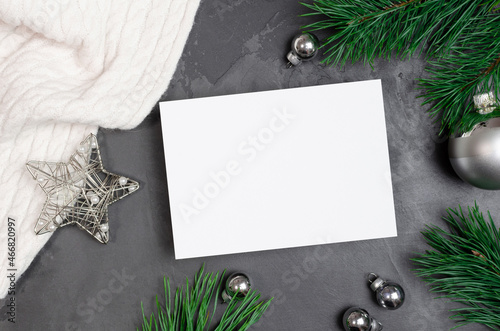 Christmas greeting card mockup with silver festive decorations and pine tree branches on dark background