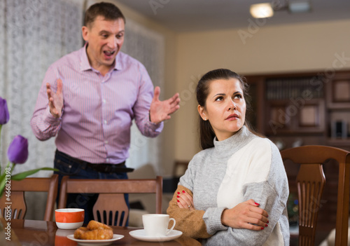 Frustrated woman sitting separately at home while dissatisfied man angrily rebuking her. Family conflicts concept