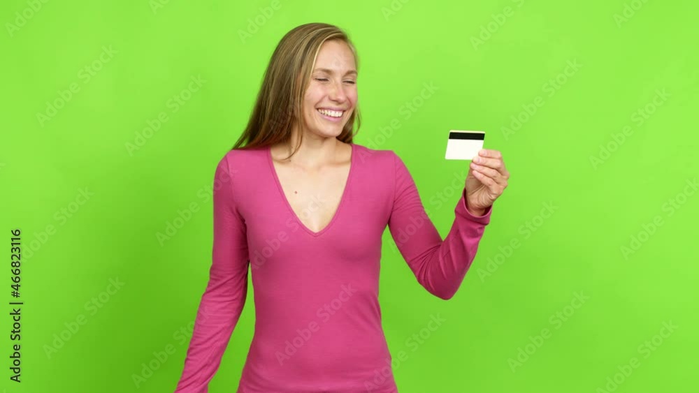 Young blonde girl surprised and holding a credit card over isolated background. Green screen chroma key Young blonde girl surprised and holding a credit card over isolated background. Green screen chroma key