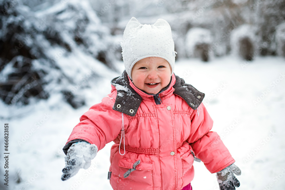 baby threw snowball and closed eyes from snow that got in face. Walking with the baby in fresh air. Hardening procedures for children under one year old outdoor in winter.