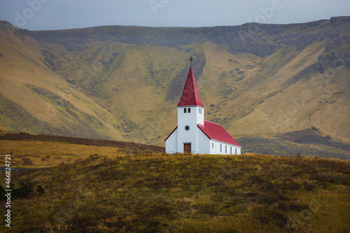White church Vikurkirkja with red roof in Vik i Myrdal with mountain in background - Iceland
