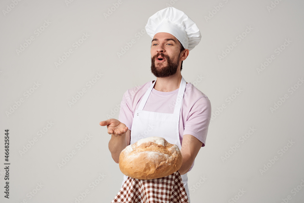 Cheerful male baker holding bread in hands preparing food light background Cheerful male baker holding bread in hands preparing food light background