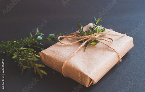 Craft gift box with knot natural with green leaves on black background