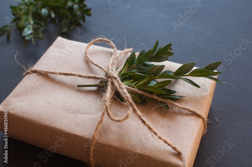 Craft gift box with knot natural with green leaves on black background