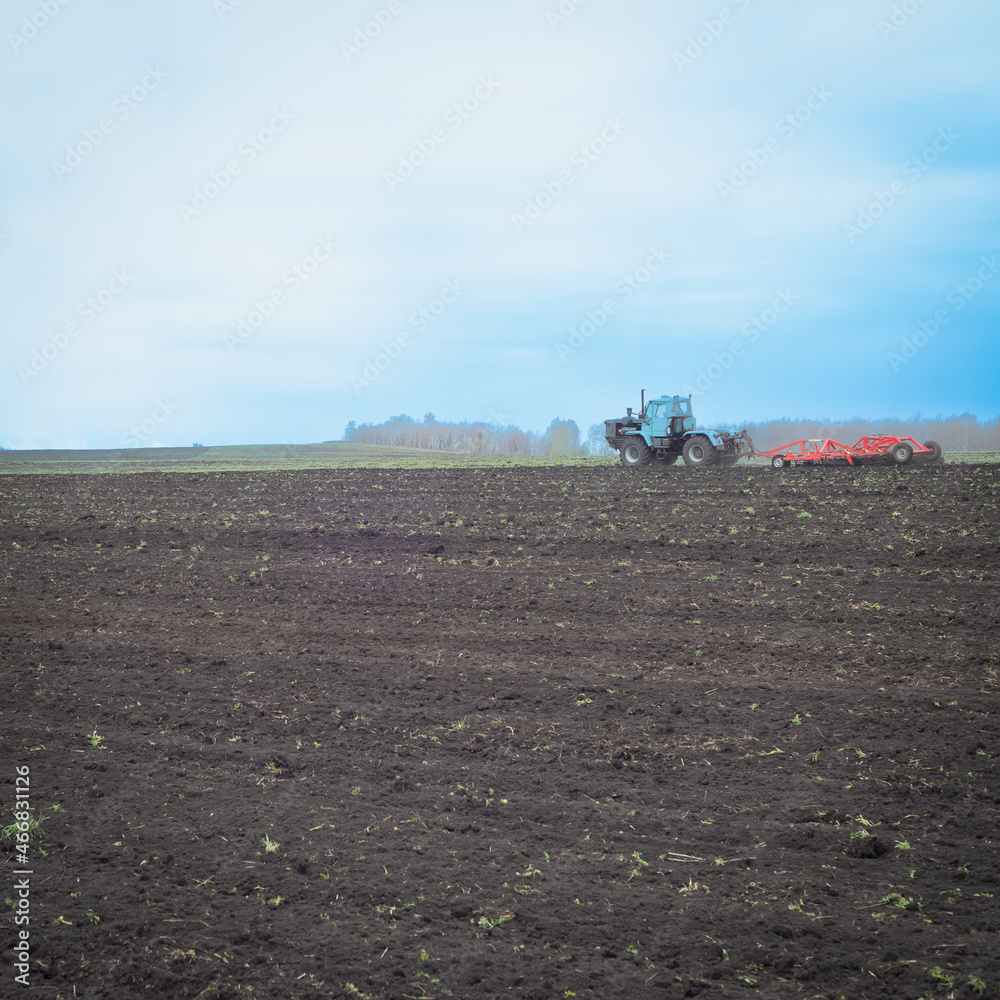 Fototapeta premium In the field, work is underway on plowing the land with tractors.