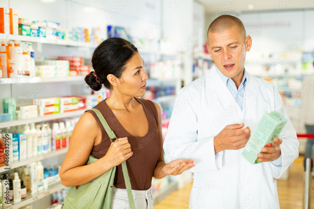 Female buyer consults the pharmacist which lotion or ointment to buy at the pharmacy