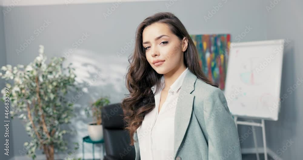 A beautiful woman is standing sideways to camera in company's office, looking out the window, she turns around and puts arms crossed over her chest and smiles sympathetically, confidently A beautiful woman is standing sideways to camera in company's office, looking out the window, she turns around and puts arms crossed over her chest and smiles sympathetically, confidently
