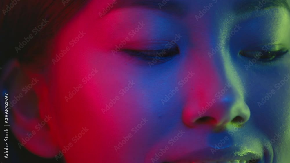 Close up portrait of young pretty asian woman posing to camera in bright colorful neon lights and smiling Close up portrait of young pretty asian woman posing to camera in bright colorful neon lights and smiling