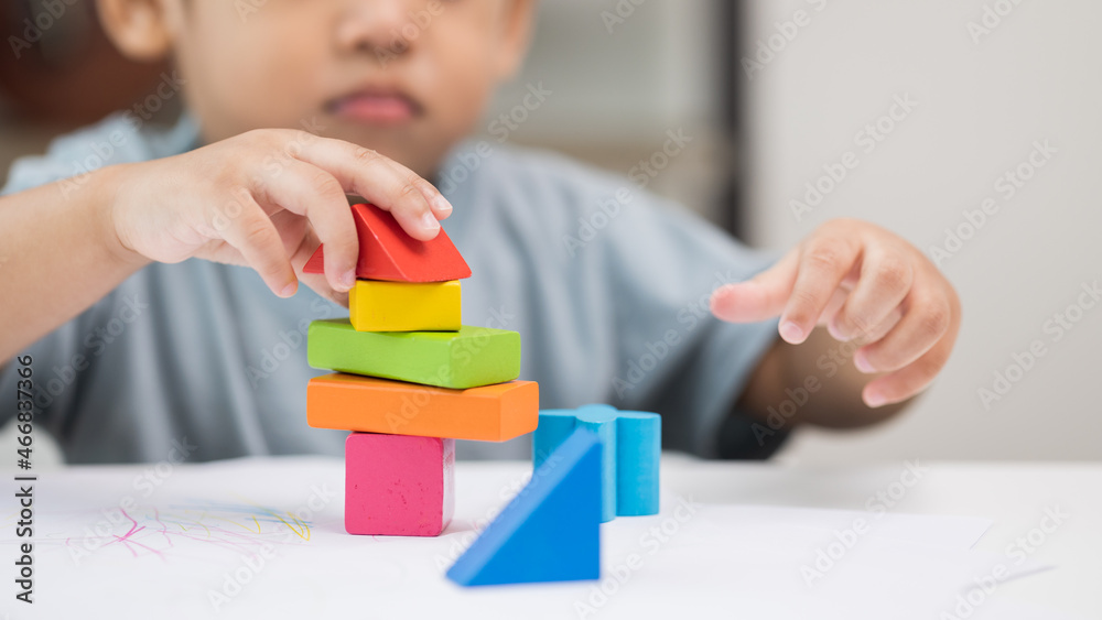 Close up Children hand Practice the skills of playing with wooden toys on the table in living room. Asian little boy education from home. Developing children's learning before entering kindergarten Close up Children hand Practice the skills of playing with wooden toys on the table in living room. Asian little boy education from home. Developing children's learning before entering kindergarten