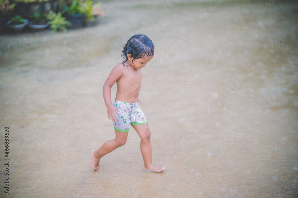 Happy asian little child girl having fun to play with the rain in the evening sunlight Happy asian little child girl having fun to play with the rain in the evening sunlight