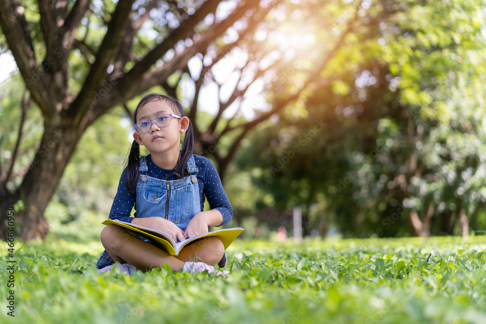 Asian little child girl with book in the garden Asian little child girl with book in the garden