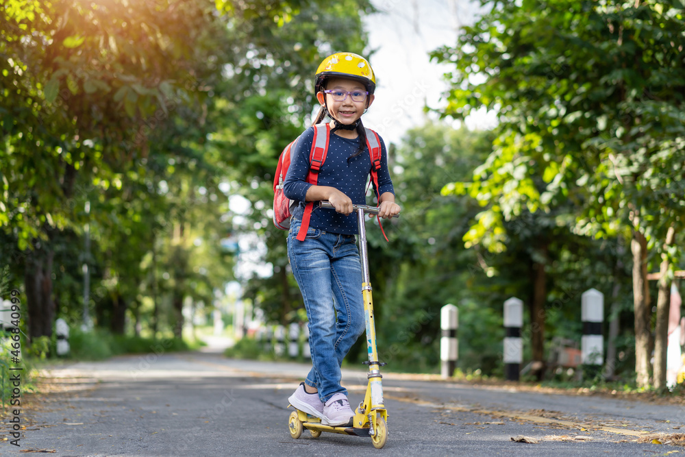 Happy Asian school girl ride a scooter to school idea concept