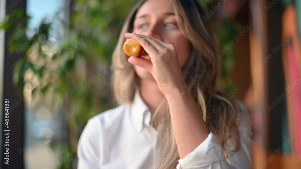 Happy woman drinking fresh ginger juice from a small plastic bottle