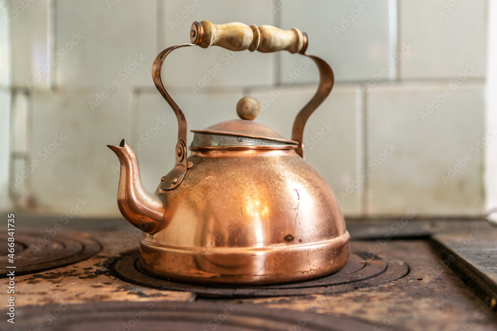 Close-up of a vintage brass teapot on an old wood stove Stock