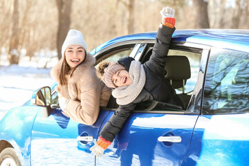 Happy mother and daughter sitting in car on winter day