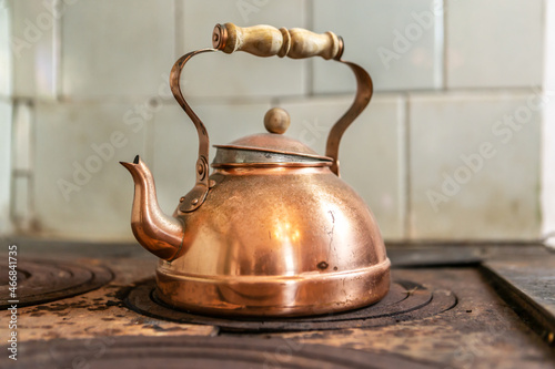 Close-up of a vintage brass teapot on an old wood stove photo