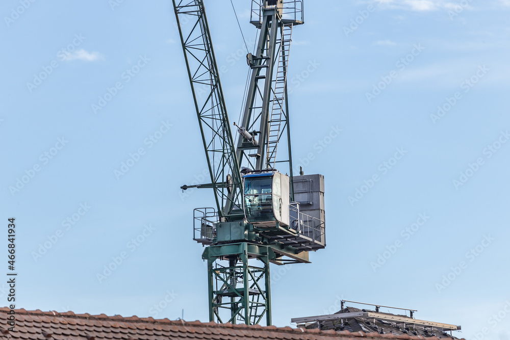 Steeple cab of a tower crane above a roof Steeple cab of a tower crane above a roof