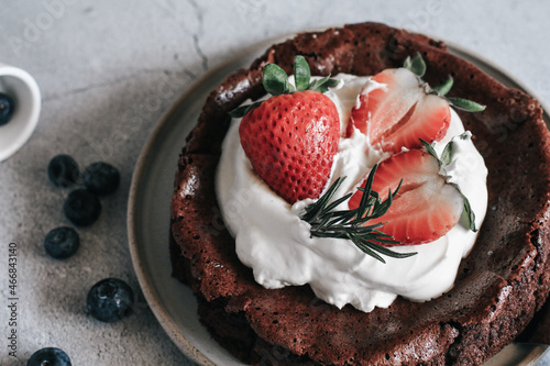 Flourless chocolate cake with whipping cream and strawberry on concrete background. Homemade cake concept.