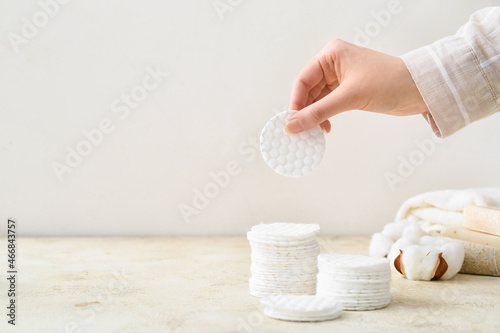 Female hand with new clean cotton pad on light background photo