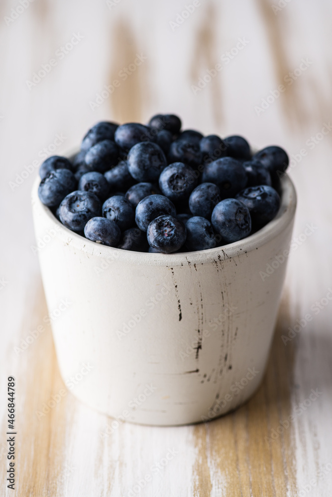 Blueberries in white ceramic bowl on rustic wooden background. Selective focus. Shallow depth of field. Blueberries in white ceramic bowl on rustic wooden background. Selective focus. Shallow depth of field.