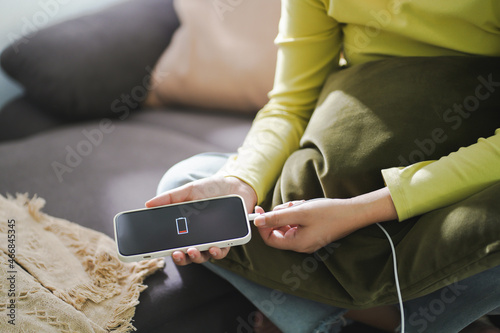 Woman hands Charging mobile phone battery with low battery. plugging a charger in a smart phone  with energy bank powerbank power charger Modern lifestyle energy technology concept. photo