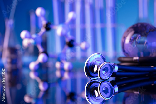 Laboratory investigations concerning test and medicine against covid. Microscope, shethoscope, glass tubes and beakers on blue background. photo