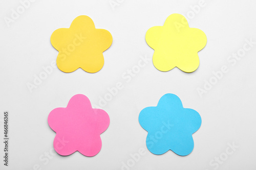 Sticky notes in shape of flowers on white background